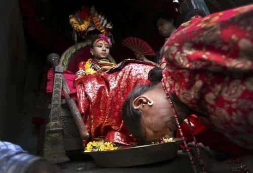 A woman bowing down to touch the feet of a living deity to receive blessings.