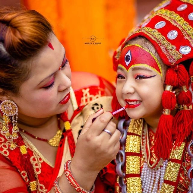 A woman doing the makeup of Goddess Kumari