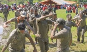 People dance in the mud on national paddy day.